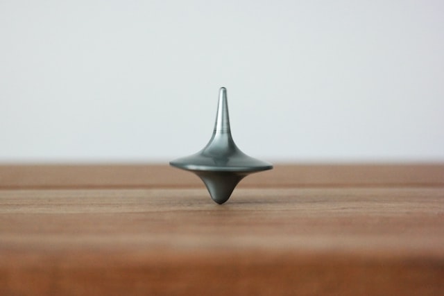 A metal top spinning on a wooden table.