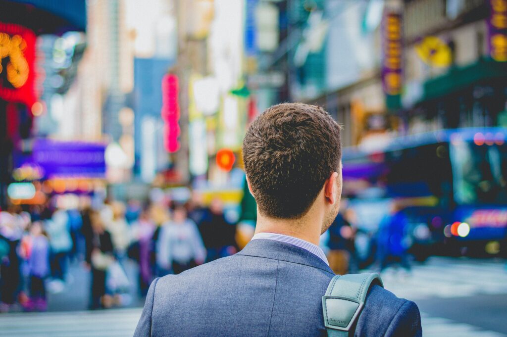 A man in a suit carrying a bag, walking through a busy city street.